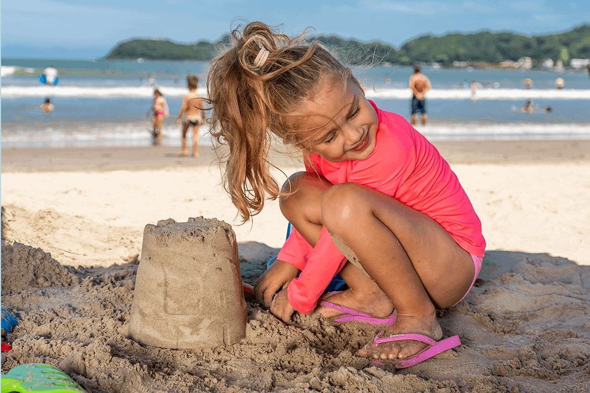 menina fazendo castelo de areia