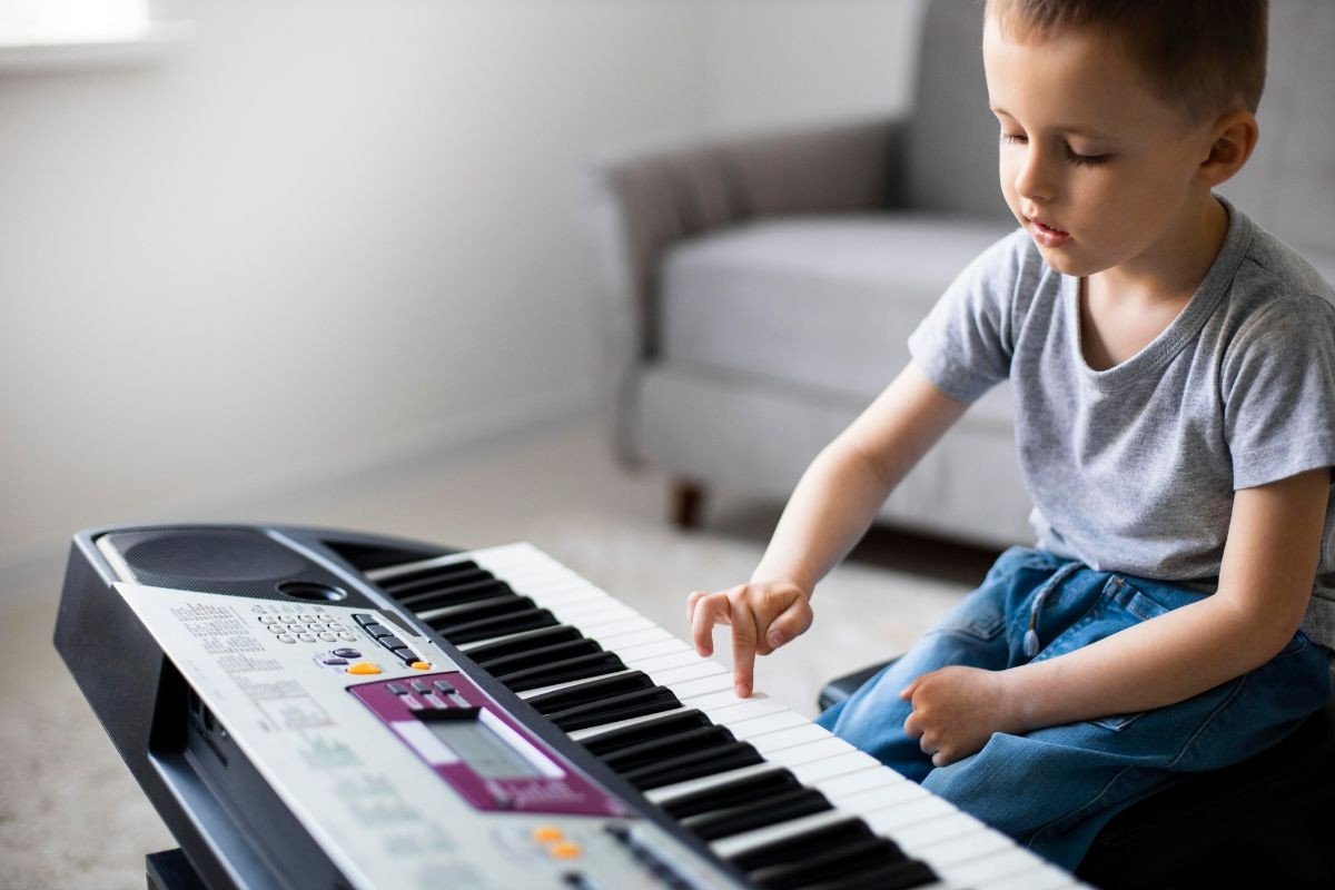menino com teclado musical aprendendo com a musicalizacao